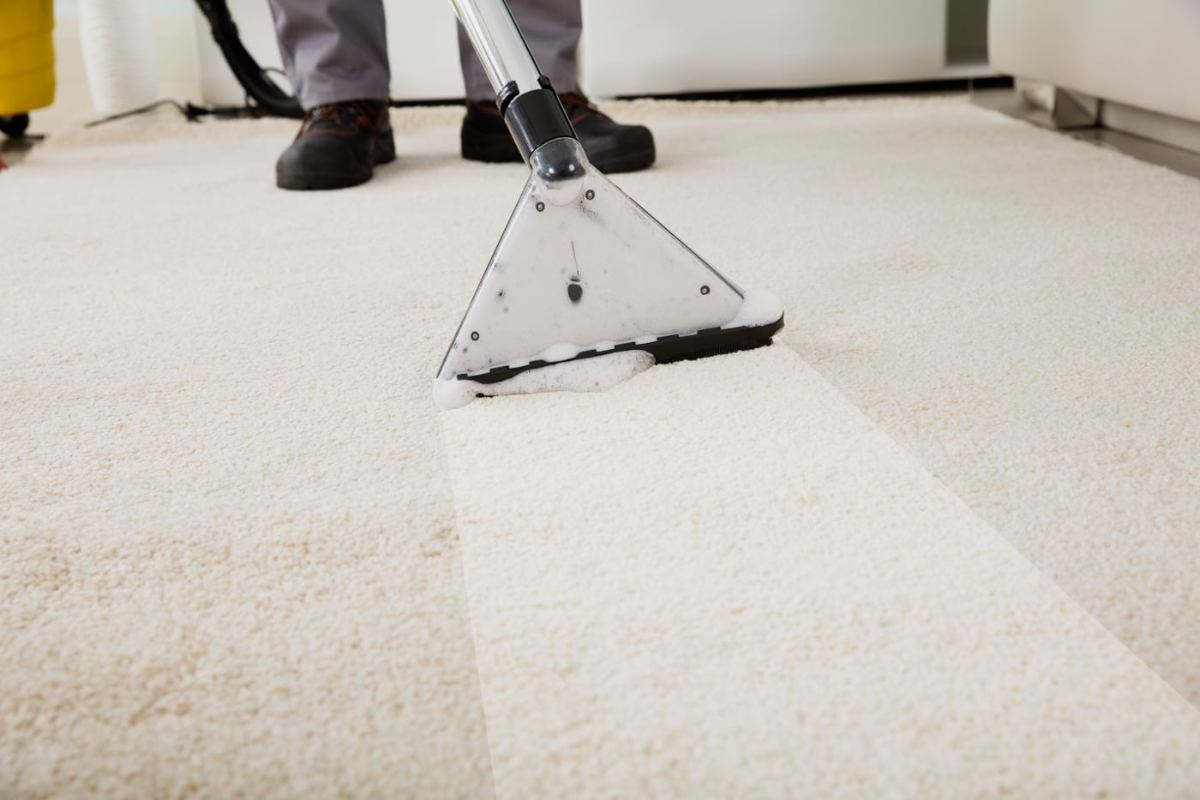 Extraction wand pulling soil from a cream carpet